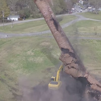  (Video) Chimenea de casi 50 metros de altura sepulta a excavadora al ser derrumbada