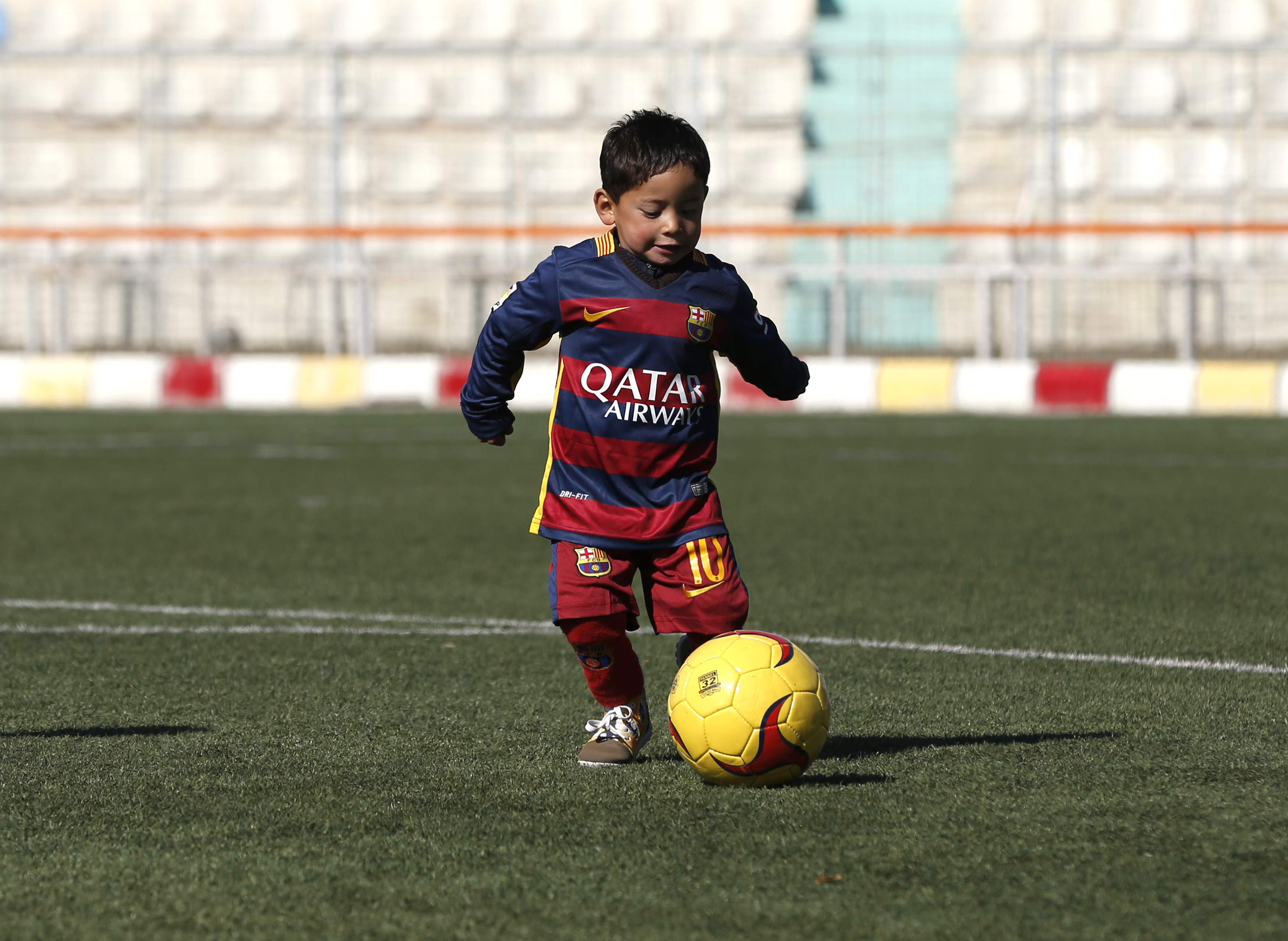 Five year-old Murtaza Ahmadi wears a shirt of Barcelona's star Lionel Messi as he plays soccer at the Afghan Football Federation headquarters in Kabul